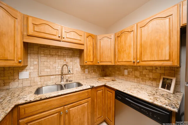 a kitchen with granite countertop a sink a stove and cabinets