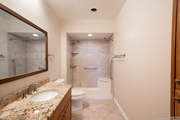 a bathroom with a granite countertop sink a mirror and a toilet
