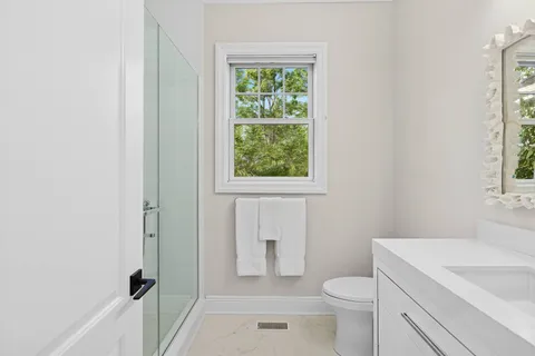 a bathroom with a granite countertop toilet a sink and a window