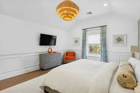 a bedroom with a bed and a flat tv screen on the dresser