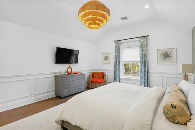 a bedroom with a bed and a flat tv screen on the dresser