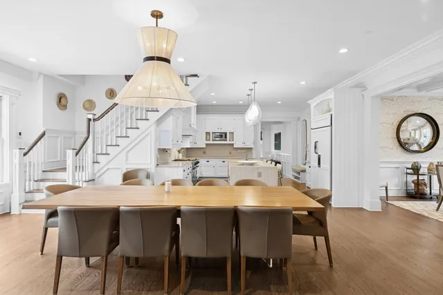 a dining room with wooden floor a chandelier a wooden table and chairs