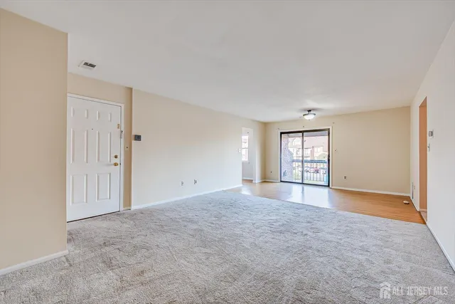 a view of an empty room with window and wooden floor
