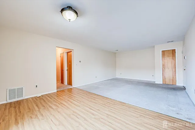a view of empty room with window and wooden floor