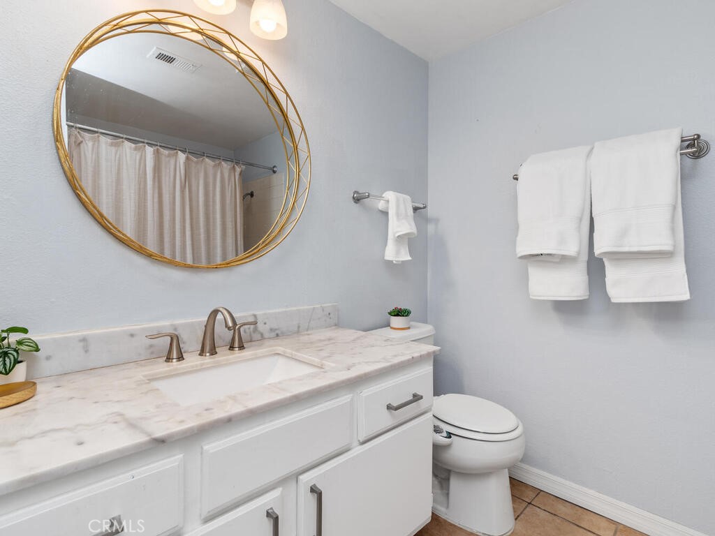 6907 Quail Place, Unit F Carlsbad, CA 92009 - Photo 15 of 24 a bathroom with a granite countertop toilet sink mirror and vanity