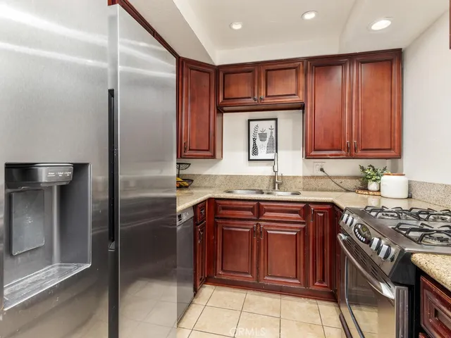 a kitchen with stainless steel appliances granite countertop a stove top oven a refrigerator and cabinets