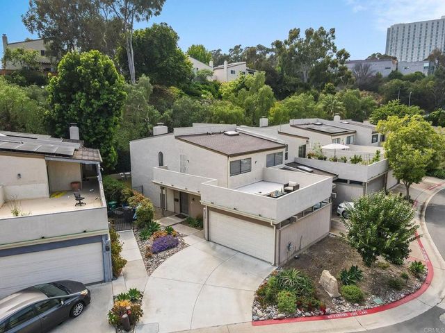 a white house with lots of flower plants in front of it