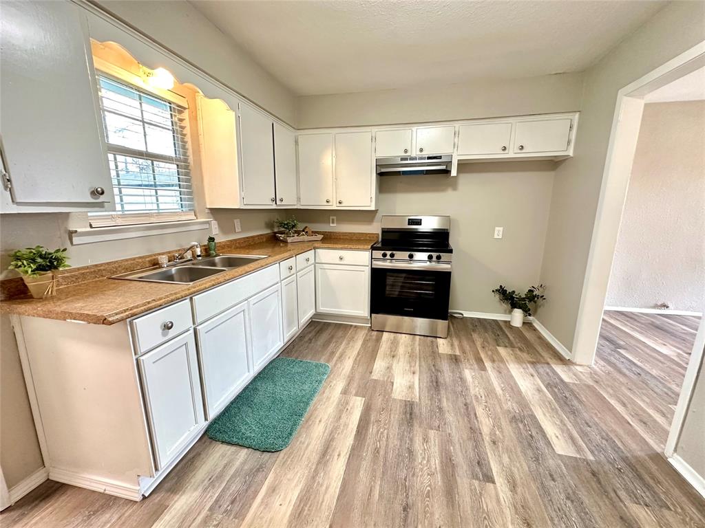 504 Bales Street Cleburne, TX 76033 - Photo 5 of 11 a kitchen with a sink a stove a refrigerator and cabinets