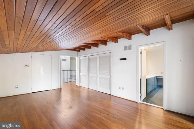 a view of an empty room with wooden floor and windows