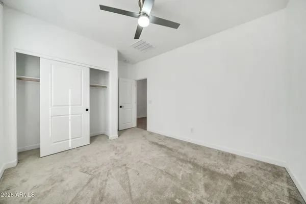 an empty room with a ceiling fan and closet area