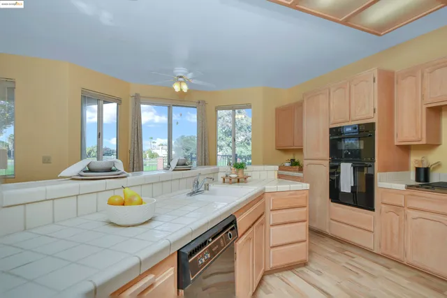 a kitchen with stainless steel appliances granite countertop a sink a stove cabinets counter space and living room view