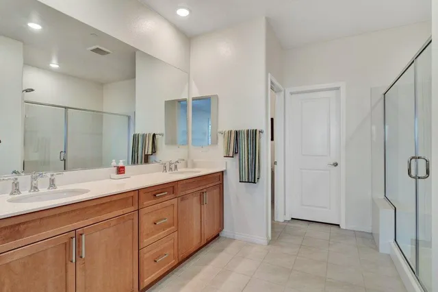 a spacious bathroom with a double vanity sink a mirror and shower