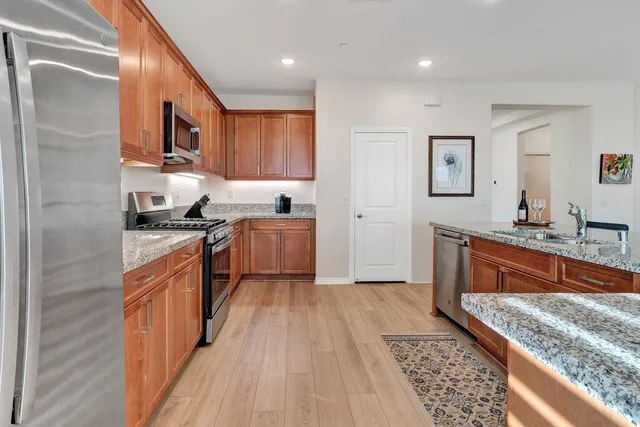 a kitchen with stainless steel appliances granite countertop a stove a sink and a refrigerator