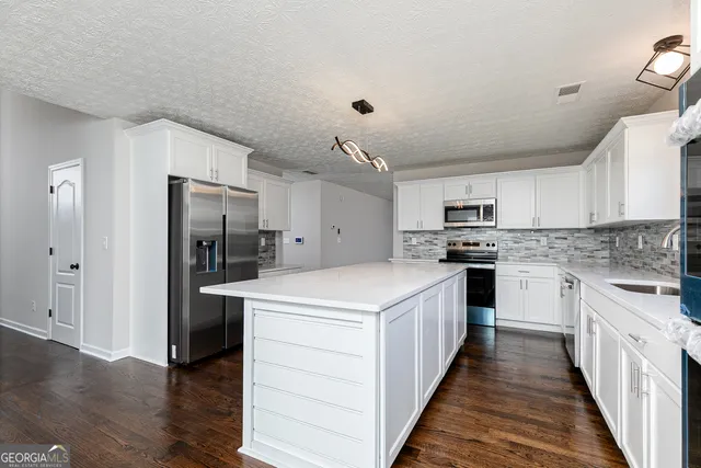 a kitchen with stainless steel appliances kitchen island a refrigerator sink and cabinets