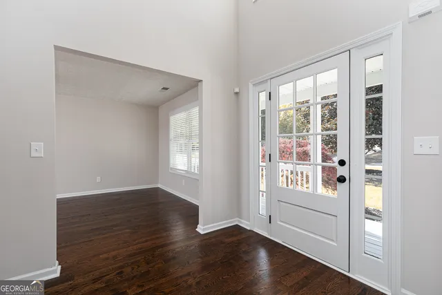 a view of an empty room with window and wooden floor