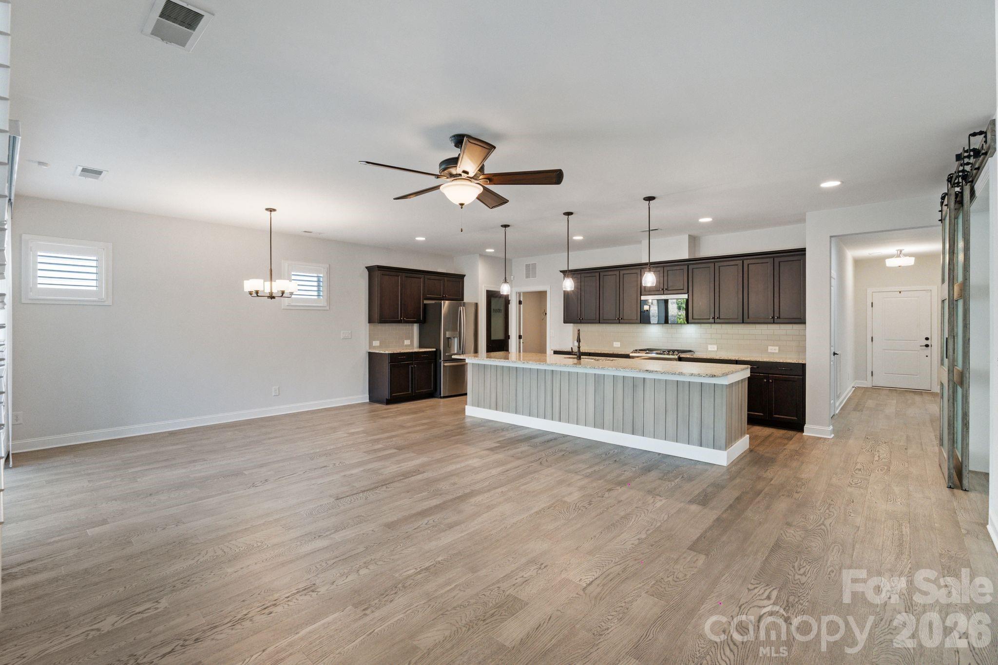4995 Looking Glass Trail Denver, NC 28037 - Photo 17 of 46 a large kitchen with a refrigerator a sink dishwasher a stove and a dining table with wooden floor