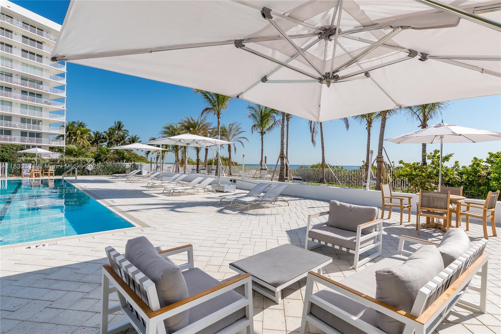 613 Ocean Drive, Unit 7C Key Biscayne, FL 33149 - Photo 29 of 42 a view of a patio with a dining table and chairs under an umbrella