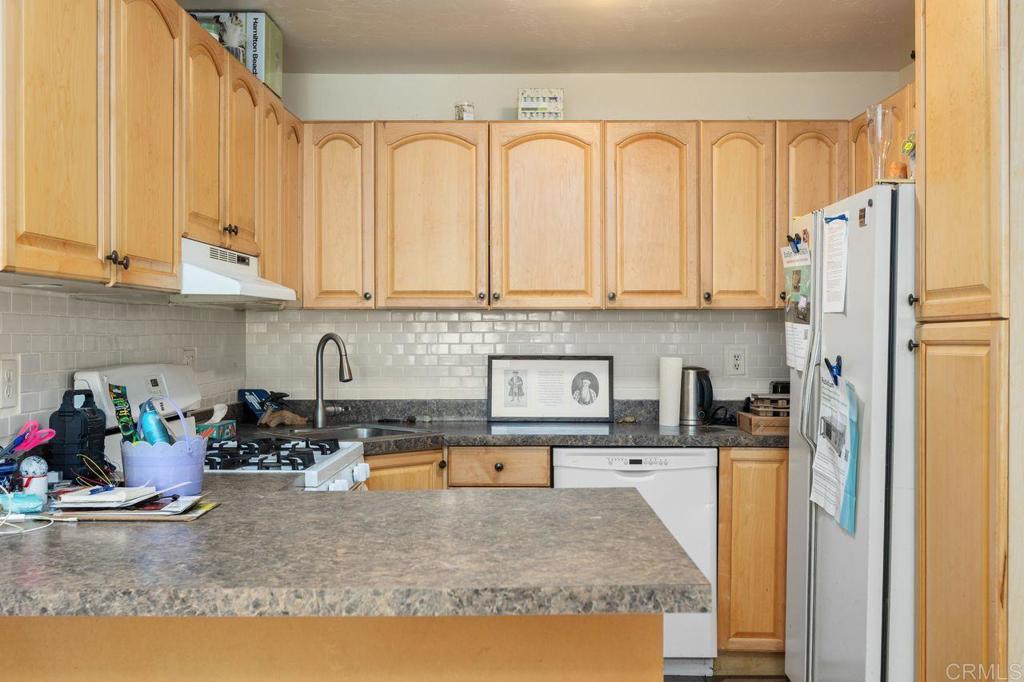 29560 Lilac Road Valley Center, CA 92082 - Photo 28 of 43 a kitchen with stainless steel appliances granite countertop a refrigerator a sink and white cabinets