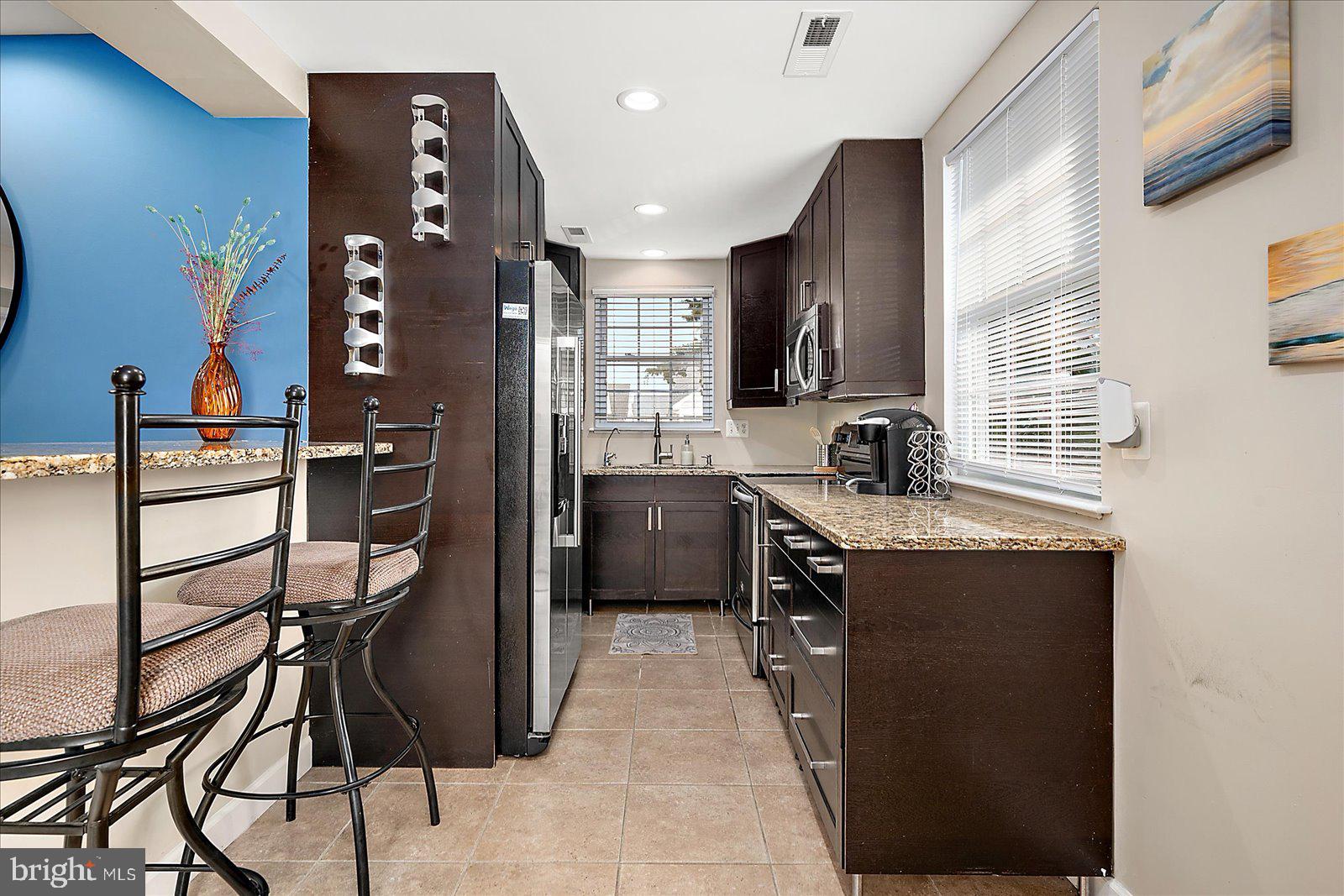 10428 Exeter Road Ocean City, MD 21842 - Photo 17 of 56 a kitchen with kitchen island granite countertop wooden cabinets and stainless steel appliances