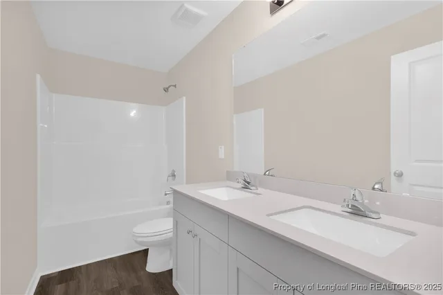 a bathroom with a double vanity sink toilet mirror and bathtub