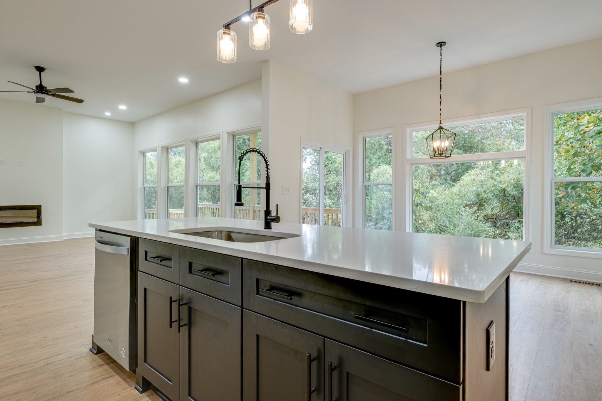 a view of kitchen with kitchen island a sink appliances cabinets and a large window