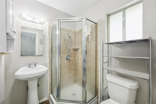 a bathroom with a shower sink mirror and toilet