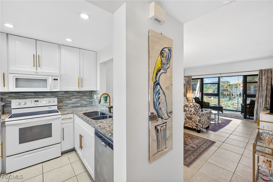 801 River Point Drive, Unit 203A Naples, FL 34102 - Photo 11 of 32 a kitchen with stainless steel appliances granite countertop a stove a sink and a refrigerator