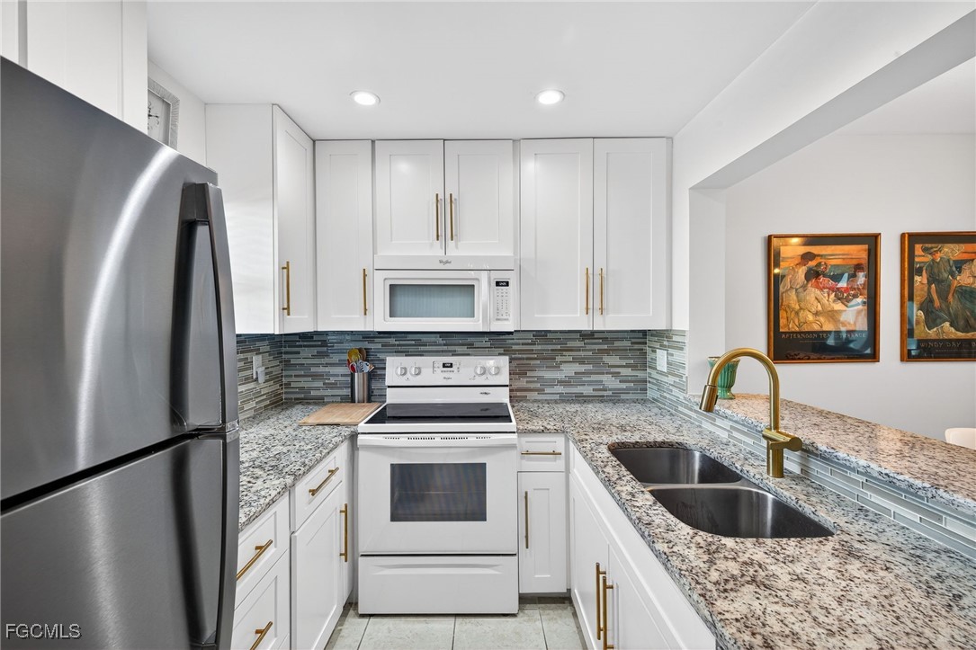 801 River Point Drive, Unit 203A Naples, FL 34102 - Photo 12 of 32 a kitchen with granite countertop a refrigerator sink and stove