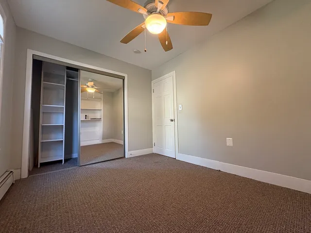 an empty room with closet and a chandelier fan