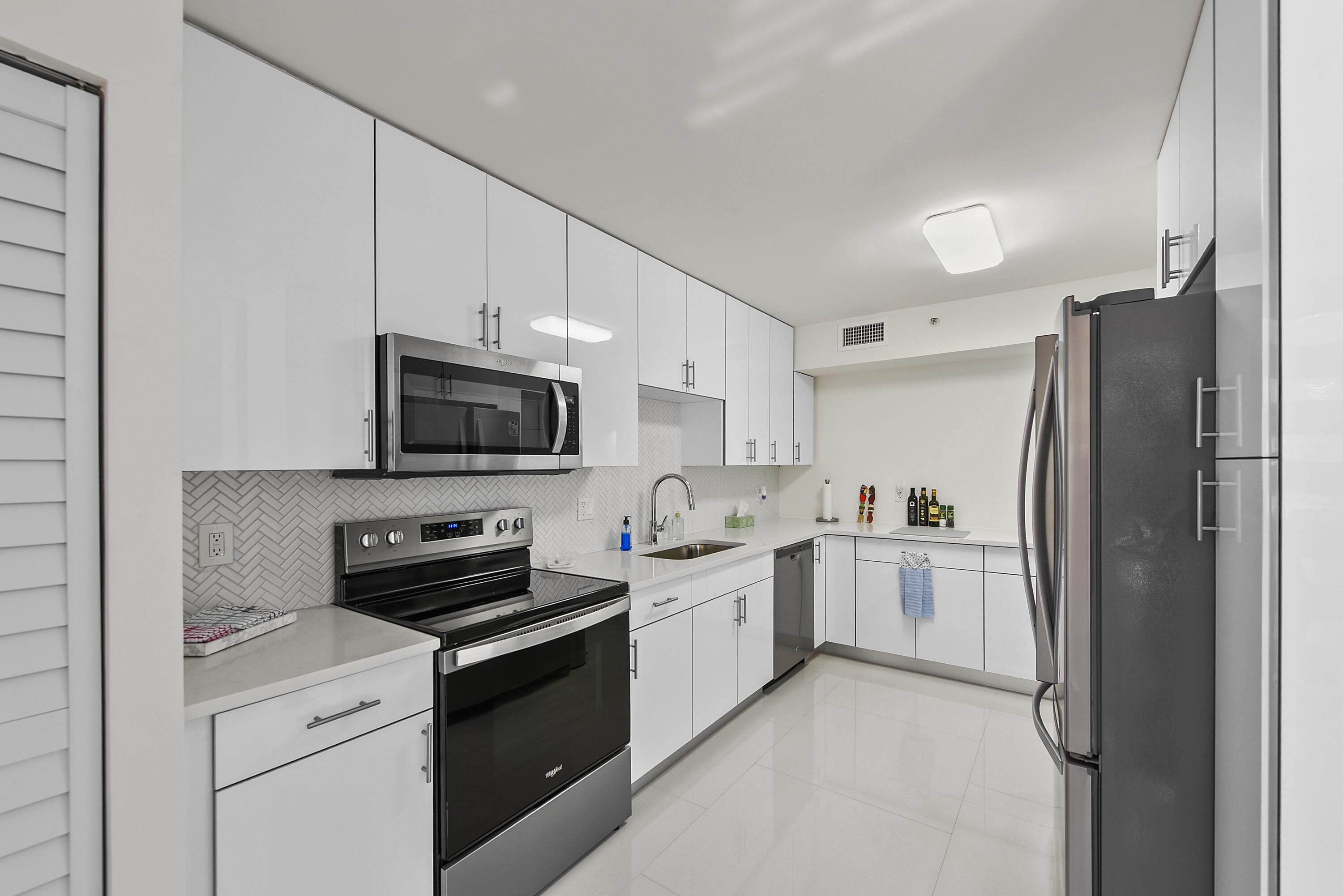 7145 Promenade Drive, Unit 101 Boca Raton, FL 33433 - Photo 4 of 24 a kitchen with a sink stainless steel appliances and cabinets