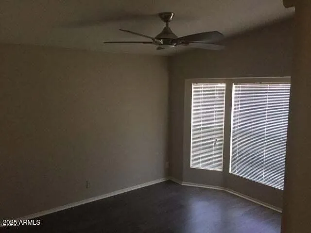 an empty room with wooden floor fan and windows