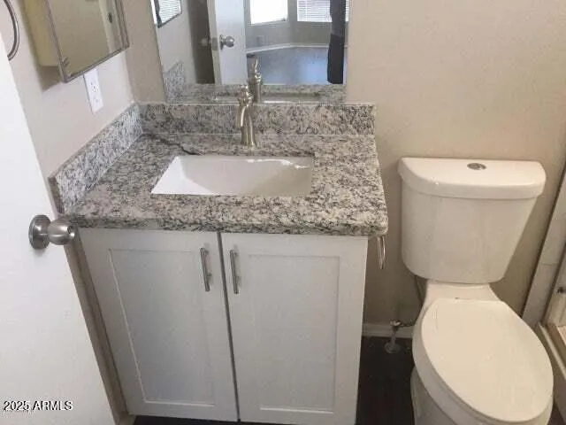 a bathroom with a granite countertop toilet sink and mirror