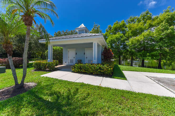 Undisclosed Address Stuart, FL 34994 - Photo 32 of 41 a view of a white house with a big yard and potted plants and large trees