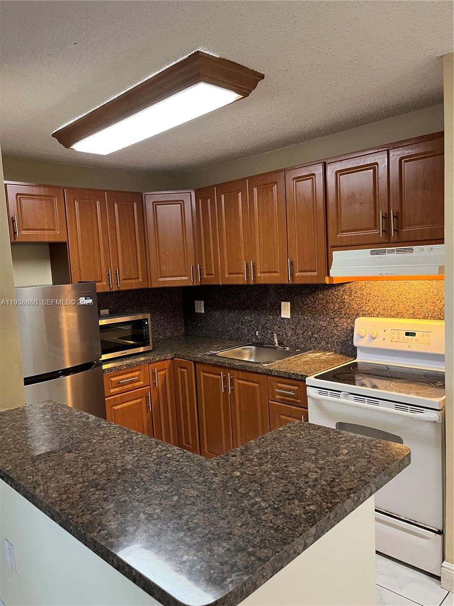 15630 Southwest 80th Street, Unit I110 Miami, FL 33193 - Photo 7 of 28 a kitchen with stainless steel appliances granite countertop a stove a sink and a microwave