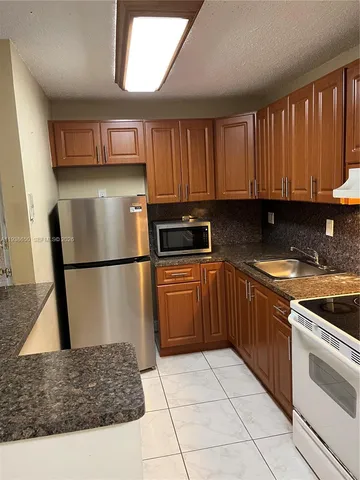 a kitchen with a sink a refrigerator and cabinets