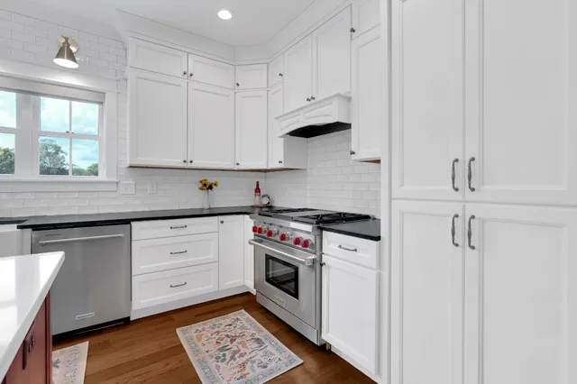 a kitchen with granite countertop a refrigerator and white cabinets