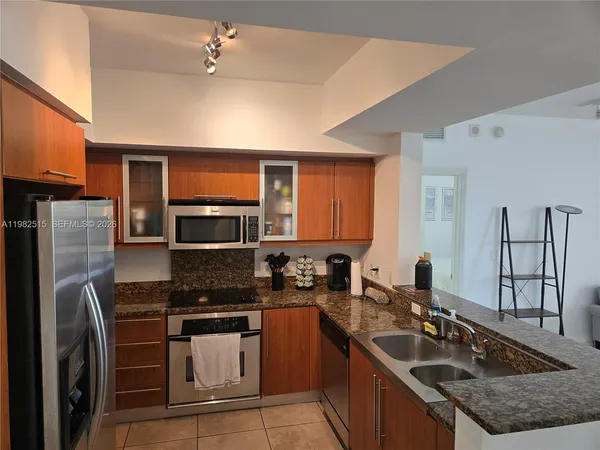 a kitchen with stainless steel appliances granite countertop a sink stove microwave and refrigerator