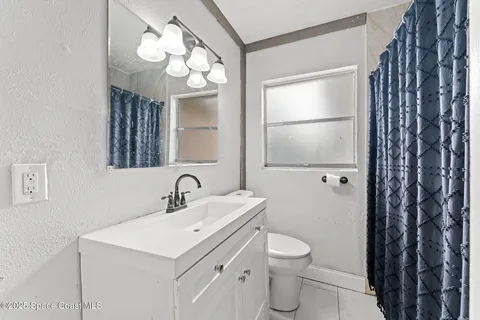 a bathroom with a toilet a sink a mirror and a shower