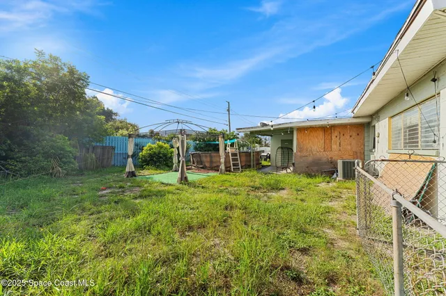 a backyard of a house with plants and large tree