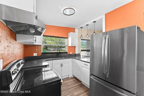 a kitchen with stainless steel appliances granite countertop a refrigerator a sink and white cabinets