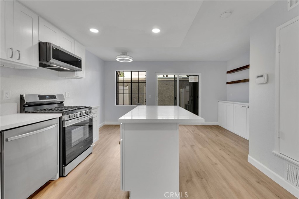 8703 Pine Crest Place Rancho Cucamonga, CA 91730 - Photo 11 of 36 a kitchen with stainless steel appliances granite countertop a sink a stove top oven and wooden floors