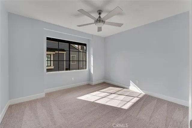 an empty room with windows and ceiling fan
