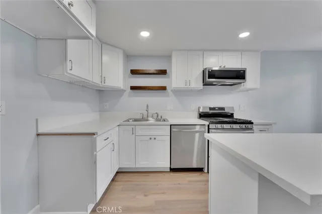 a kitchen with stainless steel appliances a sink dishwasher a stove and white cabinets
