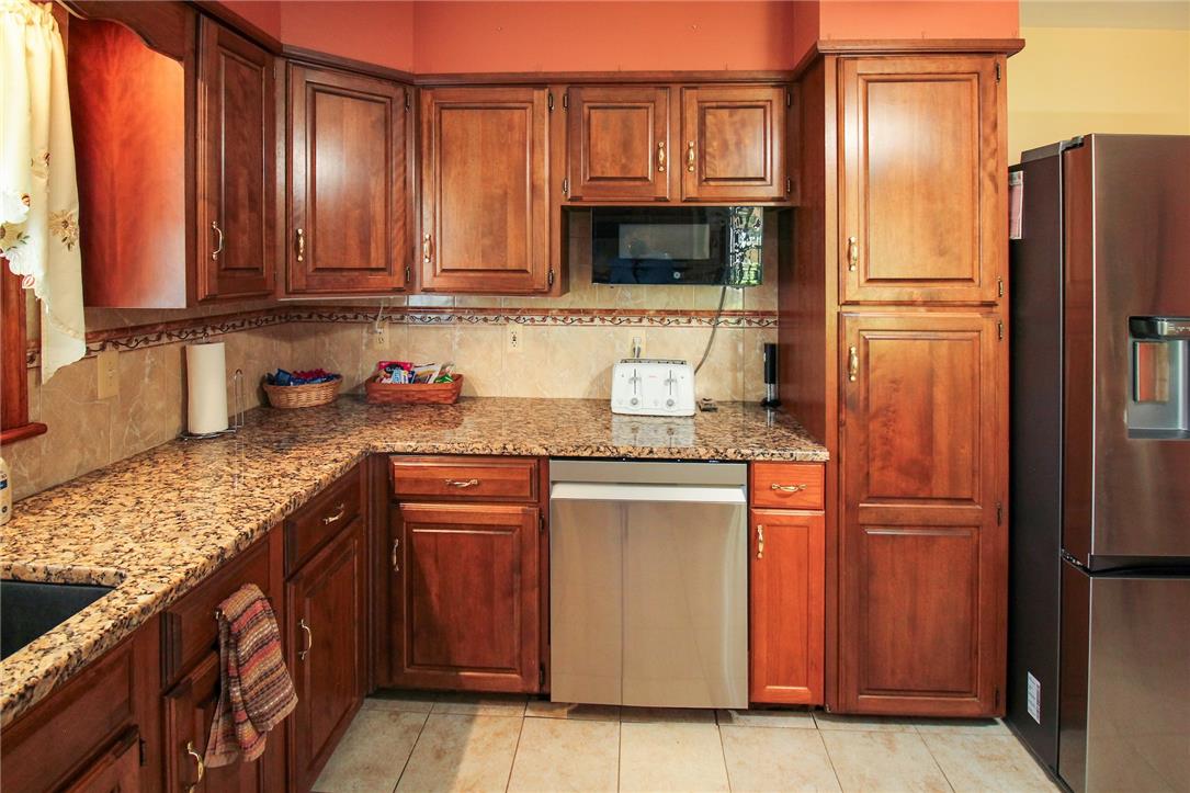1256 Ridge Avenue Whitehall, PA 18052 - Photo 21 of 43 A well-appointed kitchen features rich wood cabinetry, speckled granite countertops, and light-colored tiled floors.