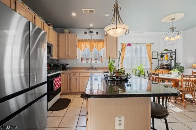 a kitchen with stainless steel appliances granite countertop a refrigerator and a dining table