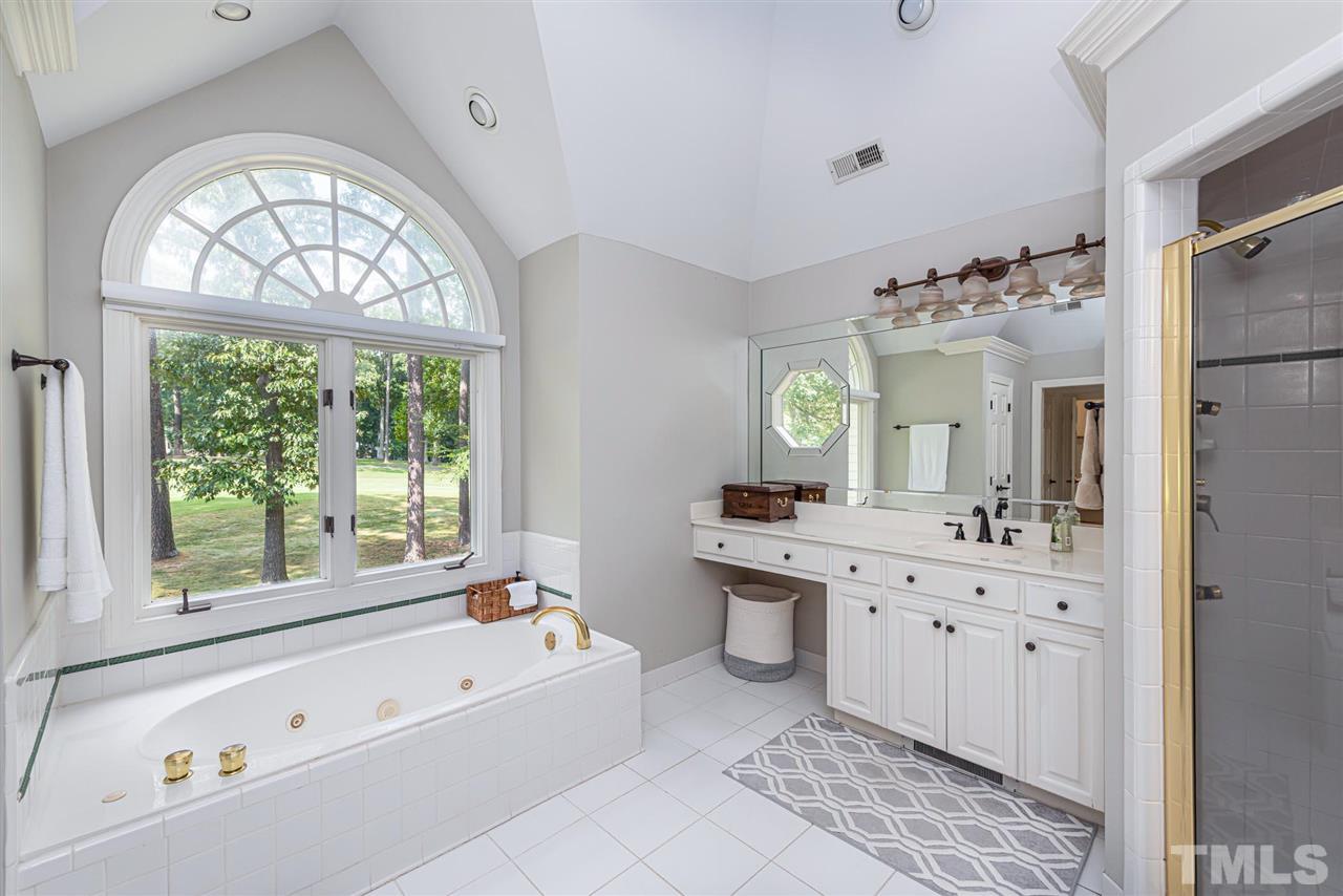 7016 North Ridge Drive Raleigh, NC 27615 - Photo 16 of 30 a bathroom with a bathtub a sink a large mirror and a bathtub next to a window