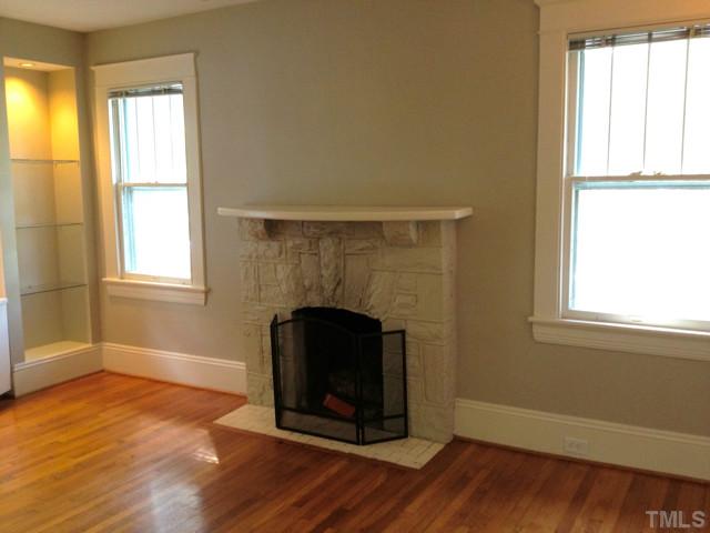 108 Duncan Street Raleigh, NC 27608 - Photo 3 of 5 an empty room with wooden floor a fireplace and windows