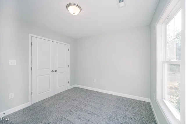 an empty room with windows and closet