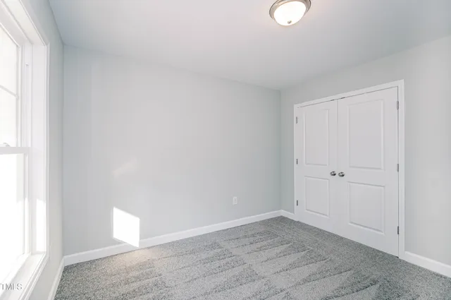 a view of an empty room with a window and hardwood floor
