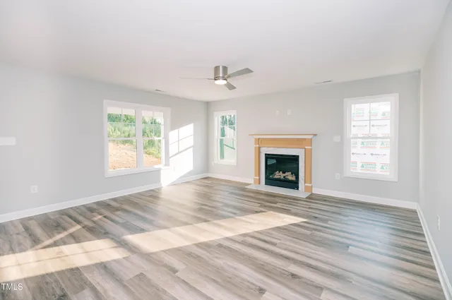 an empty room with windows fireplace and a sink